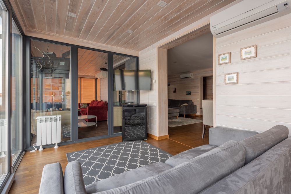 Dark-framed glass doors separating comfortable contemporary living spaces